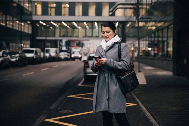 IMAGO Creative: Corporate: Klimaschutz, Digitalisierung und Urbanisierung Businesswoman using smart phone while standing on city street against building , model released Copyright: xMaskotx , MA69262