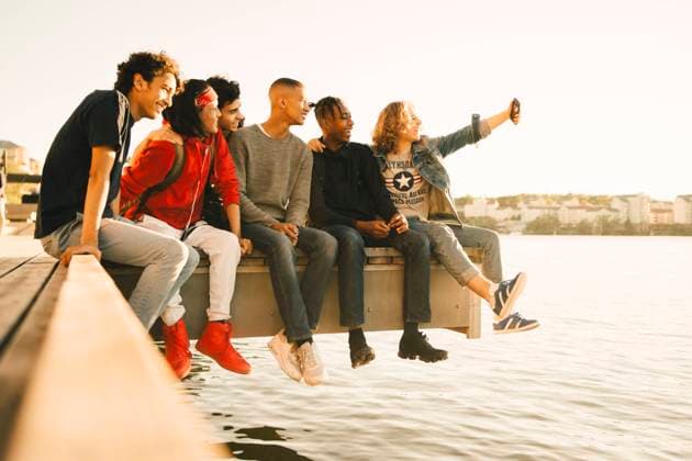 IMAGO Creative, Jahreszeit Sommer, Sommer in der Stadt Happy male friends taking selfie while sitting side by side on pier by river , model released Copyright: xMaskotx , MA69364