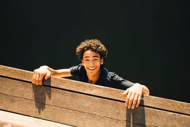 IMAGO Creative, Jahreszeit Sommer, Sommer in der Stadt High angle portrait of cheerful teenage boy hanging from pier against river , model released Copyright: xMaskotx , MA69374