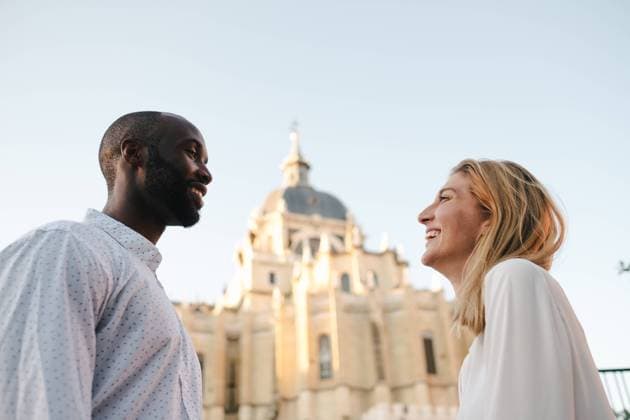 IMAGO Creative: Urban Diversity Side view happy smiling multiethnic couple in white shirts standing on street and looking at each other against old architecture in Madrid, Model released Copyright: xJakexJakabx MR