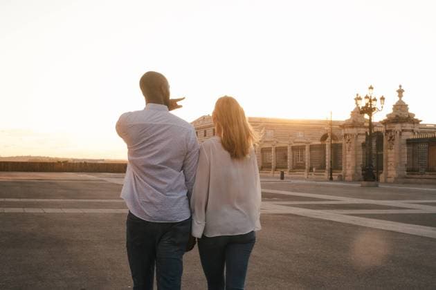 IMAGO Creative: Sommer, Abendspaziergang Back view anonymous diverse couple in casual outfits walking together along asphalt sidewalk on street during sunset time, Model released Copyright: xJakexJakabx MR