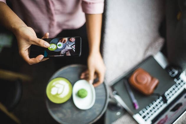 Midsection of female blogger photographing matcha tea and snack through smart phone at creative office , model released, property released Copyright: xMaskotx , MA70074