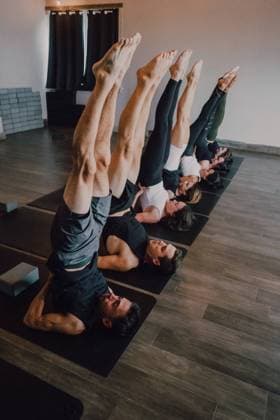 IMAGO Creative: Clickbait, Sport und Fitness From above of group of adult sporty people in sportswear with legs raised stretching body in salamba sarvangasana pose on sports mats while practicing yoga in modern studio, Model released, Property released Copyright: xJakexJakabx MR
