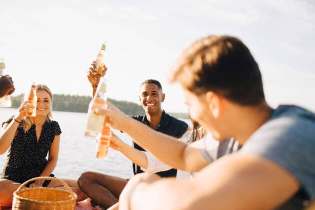 IMAGO Creative: Landleben - Essen Friends enjoying drinks while sitting on jetty against sky in summer , model released Copyright: xMaskotx , MA70447