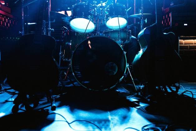 Large drum set with drums sticks and guitars on stage under blue neon light in anticipation of game Copyright: xJavierxAgundezx Model Released