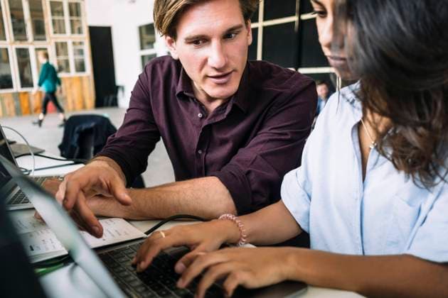 Confident male IT professional discussing with female hacker using laptop at desk in creative office , model released, property released Copyright: xMaskotx , MA71687