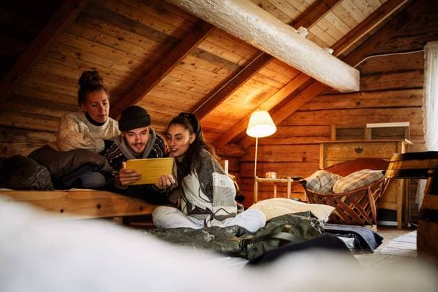 IMAGO Creative, Weihnachten, Tradition: Weihnachtsfilme sehen IMAGO Creative: Landleben, Digitalisierung auf dem Land Male and female friends watching movie over digital tablet while relaxing in cottage , model released, property released Copyright: xMaskotx , MA72155