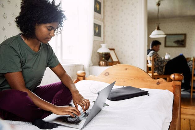 IMAGO Creative: Landleben, Digitalisierung auf dem Land Young woman using laptop on bed while friend sitting in background at home , model released, property released Copyright: xMaskotx , MA72167