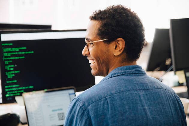 Rear view of cheerful male it professional looking away while sitting in creative office , model released, property released Copyright: xMaskotx , MA72458