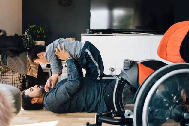 Side view of father playing autistic son while lying on floor at home , model released, property released Copyright: xMaskotx , MA72487