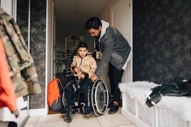 Father pushing autistic son sitting on wheelchair in corridor at home , model released, property released Copyright: xMaskotx , MA72499