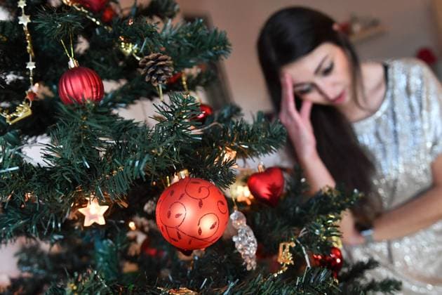 Themenbild Einsame Weihnachten 2020 in der Coronavirus Pandemie.Eine junge Frau mit Mundschutz,Maske sitzt an Heilig Abend alleine hinter ihrem Weihnachtsbaum und ist traurig. MODEL RELEASED! *** Theme Picture Lonely Christmas 2020 in Coronavirus Pandemic A young woman in a mouth guard,mask sits alone behind her Christmas tree on Christmas Eve and is sad MODEL RELEASED