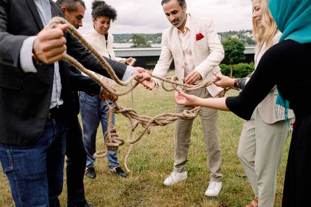 Multi-ethnic male and female colleagues holding rope while standing in lawn , model released, property released Copyright: xMaskotx , MA73818