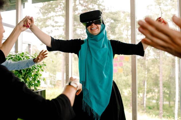 Cheerful businesswoman holding hand of colleague while using virtual reality simulator during kick off meeting at conven , model released, property released Copyright: xMaskotx , MA73826