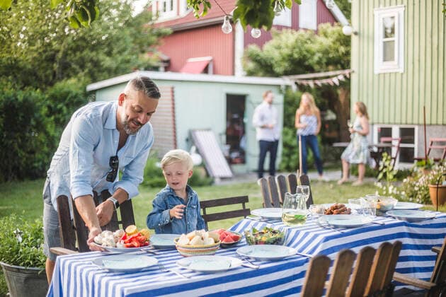 IMAGO Creative: Landleben - Essen Father talking to son while arranging food plate on table in backyard , model released, property released Copyright: xMaskotx , MA74074
