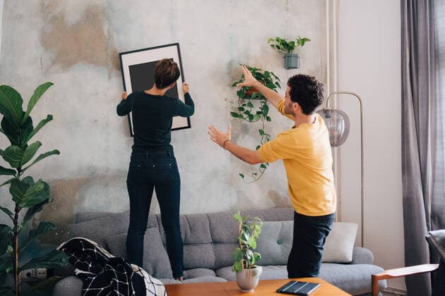 IMAGO Creative: Neue Aussichten IMAGO Creative: Clickbait, Deko Ideen für Zuhause Mid adult man guiding girlfriend in hanging picture frame on wall at new home , model released, property released Copyright: xMaskotx , MA74118