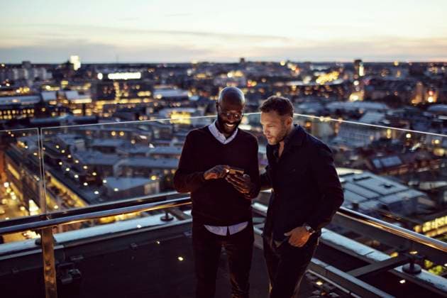 IMAGO Creative, Jahreszeit Sommer, Sommer in der Stadt Smiling businessman showing smart phone to coworker on terrace after office work in city , model released, property released Copyright: xMaskotx , MA74800