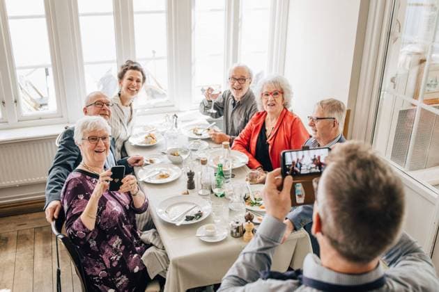 Waiter clicking photograph of Senior friends sitting in restaurant , model released, property released Copyright: xMaskotx , MA75031
