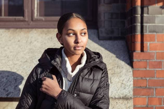 IMAGO Creative: Wintersport, Mode Thoughtful teenage girl wearing jacket looking away while sitting against wall , model released Copyright: xKentarooxTrymanx , MA75325
