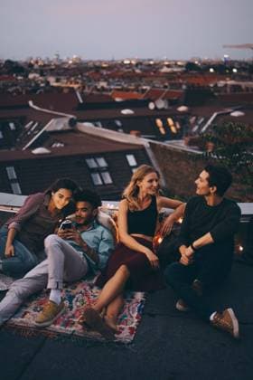IMAGO Kreativ: Urbane Kultur - Sommer auf den Dächern IMAGO Creative: Menschen in Berlin High angle view of friends relaxing together on terrace in city during rooftop party , model released, property released Copyright: xMaskotx , MA75540