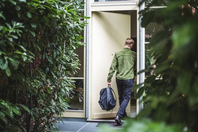 IMAGO Creative: Internationaler Tag der Architektur am 3. Oktober. Thema: Architektur zum Wohlfühlen Male entrepreneur with bag entering in house , model released, property released Copyright: xMaskotx , MA76302