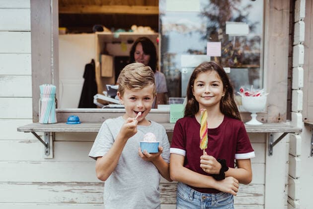 IMAGO Creative: Landleben - Essen Portrait of sibling eating sweet food while standing against concession stand , model released, property released Copyright: xMaskotx , MA76525