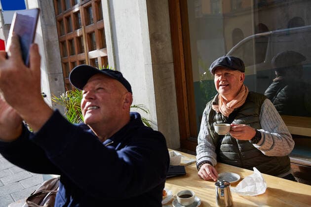 IMAGO Creative: Urban Diversity Smiling gay couple taking selfie with mobile phone while sitting at sidewalk cafe , model released Copyright: xMaskotx , MA76648