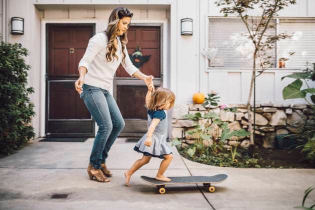 IMAGO Creative: Internationaler Frauentag, Mental Load und Care-Arbeit Daughter balancing over skateboard with help of mother on footpath , model released Copyright: xMaskotx , MA76659
