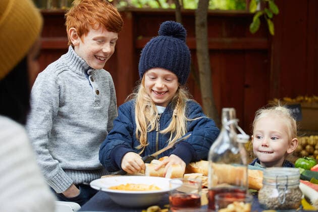 IMAGO Creative, Jahreszeit Herbst, Ferien Girl cutting bread while standing by siblings at table for garden party , model released, property released Copyright: xMaskotx , MA77140