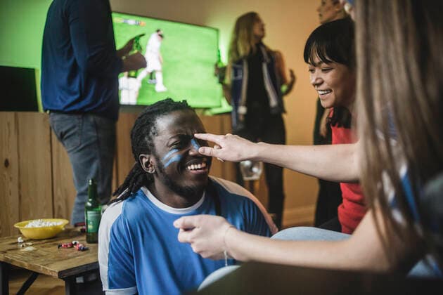 Young woman applying face paint on friend s cheek during soccer match , model released, property released Copyright: xMaskotx , MA77370