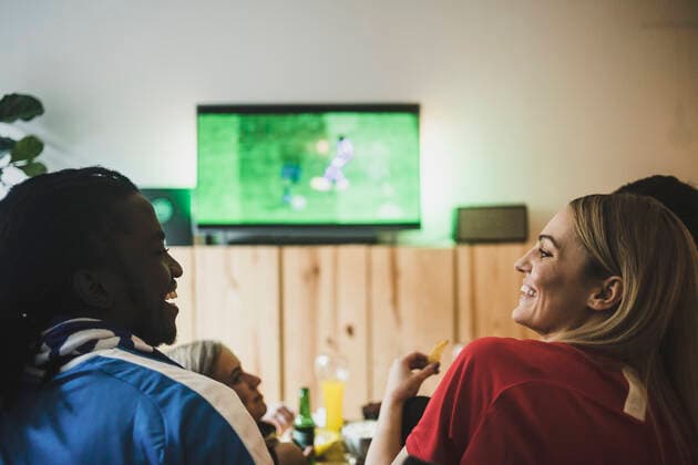 Smiling male and female watching soccer while sitting with friends at home , model released, property released Copyright: xMaskotx , MA77404