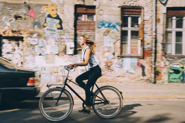 Side view of young businesswoman riding bicycle against building in city , model released Copyright: xMaskotx , MA77449