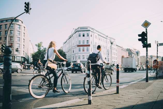 Full length of male and female entrepreneurs riding bicycle on road in city , model released Copyright: xMaskotx , MA77461
