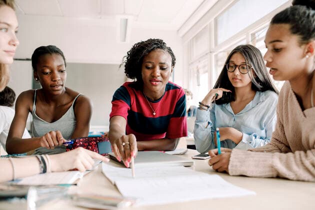 Teacher explaining while female students studying by table in classroom , model released, property released Copyright: xMaskotx , MA77564