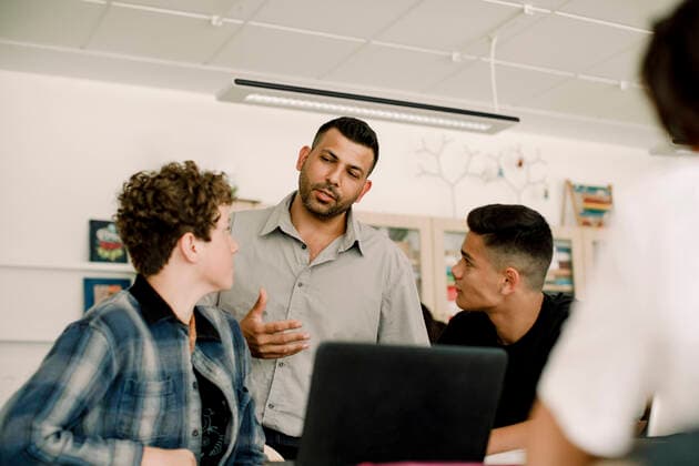 Professor discussing with male students while standing in classroom , model released, property released Copyright: xMaskotx , MA77581