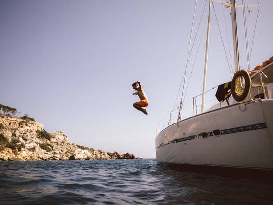 Full length side view of man jumping from catamaran into sea against sky , model released Copyright: xMaskotx , MA77683