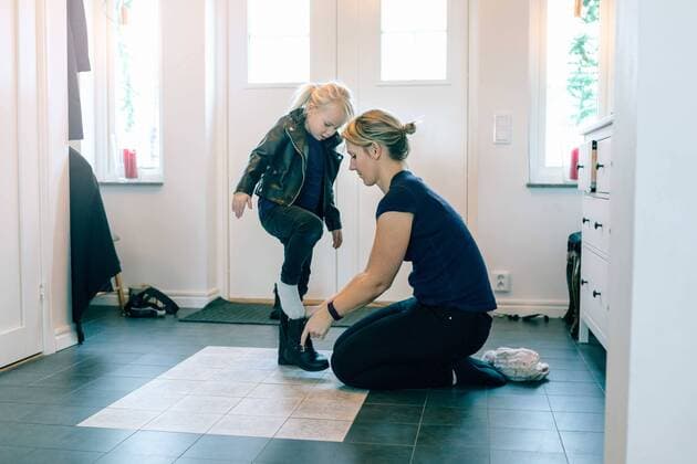 IMAGO Creative: Internationaler Frauentag, Mental Load und Care-Arbeit Mother helping daughter with shoes near door at home , model released, property released Copyright: xKentarooxTrymanx , MA77701