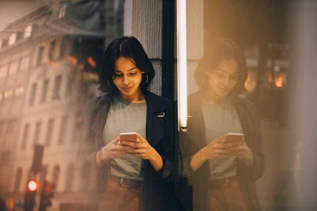 IMAGO Creative: Dichotomien, Reflexionen IMAGO Creative: Corporate: Klimaschutz, Digitalisierung und Urbanisierung Young woman texting through phone while standing by glass window , model released Copyright: xMaskotx , MA78175