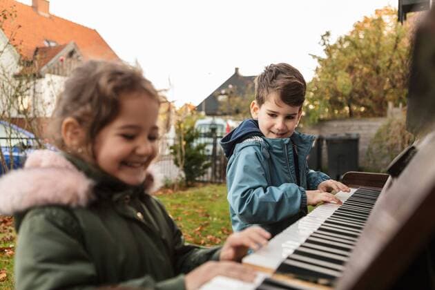 IMAGO Creative: NGO, Ausbildung für Kinder Smiling girl playing piano with brother in backyard Sweden,Malmo, model released Copyright: xKentarooxTrymanx , MA78296