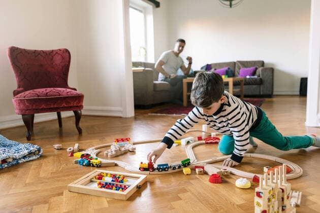 IMAGO Creative: 2021 Trends IMAGO Creative: Jahreszeit Winter, Fantasievoll drinnen spielen Son playing with miniature train while father sitting on sofa in background at home Sweden,Malmo, model released, property released Copyright: xKentarooxTrymanx , MA78315