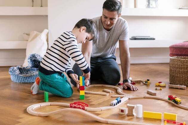 IMAGO Creative: Vaterschaft Smiling father playing with son while kneeling in living room Sweden,Malmo, model released, property released Copyright: xKentarooxTrymanx , MA78326