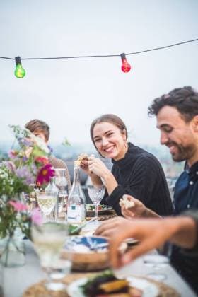 IMAGO Kreativ: Urbane Kultur - Sommer auf den Dächern Portrait of smiling female sitting with friends during social gathering on terrace , model released, property released Copyright: xMaskotx , MA78354