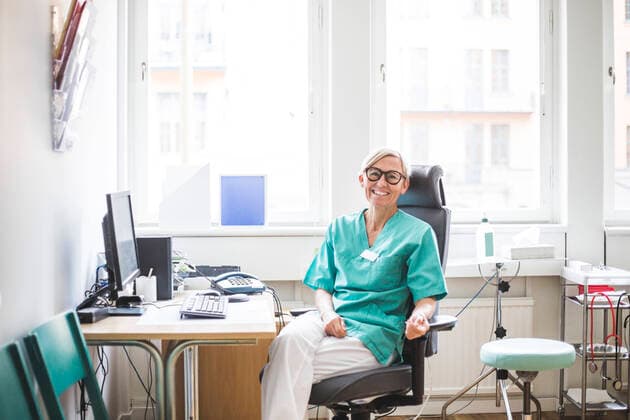 IMAGO Creative: Lokalhelden - Gesundheits- und Rettungskräfte Portrait of smiling mature female doctor sitting in clinic , model released, property released Copyright: xMaskotx , MA78700