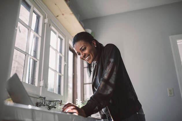 IMAGO Creative: Kreative Renaissance -- der junge Entrepreneur Smiling female professional looking at laptop while standing at home office USA, Los Angeles, model released, property released Copyright: xMaskotx , MA79068
