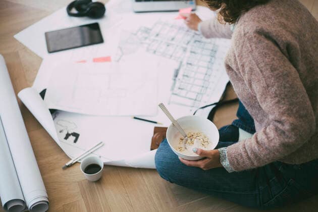 IMAGO Creative: Internationaler Frauentag, Mental Load und Care-Arbeit IMAGO Creative, Internationaler Frauenmonat, Entrepreneurinnen Woman working at home sitting on the floor looking at blueprint having breakfast Sweden, Stockholm, model released, property released Copyright: xMaskotx , MA79458