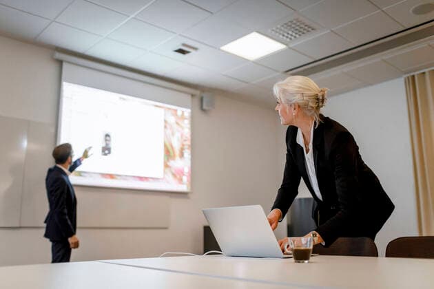 Female professional using laptop while male colleague standing by flat screen during video conference in board room at o Sweden, Stockholm, model released, property released Copyright: xMaskotx , MA79475
