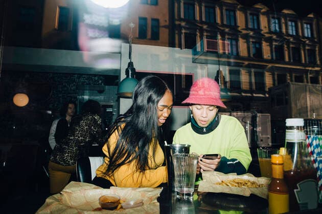 IMAGO Creative: Dichotomien, Reflexionen Man showing smart phone to smiling woman seen through transparent glass window Sweden, Stockholm, model released, property released Copyright: xMaskotx , MA79621