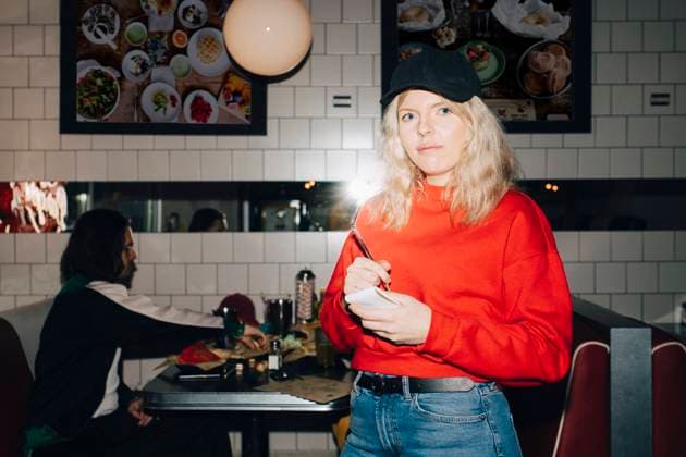 Portrait of female waitress with note pad standing against table in restaurant Sweden, Stockholm, model released, property released Copyright: xMaskotx , MA79654
