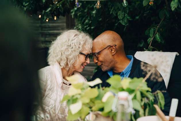 Senior female and male friends sitting face to face during garden party in back yard Sweden, Stockholm, model released, property released Copyright: xMaskotx , MA79989