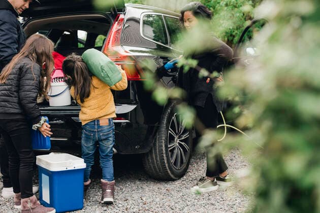 Family loading luggage in trunk while woman charging electric car Sweden, Stockholm, model released Copyright: xMaskotx , MA80106
